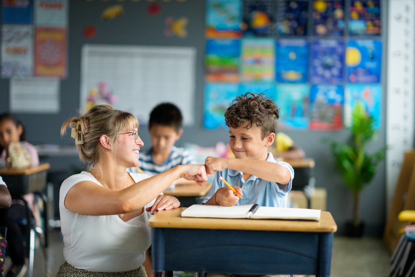 boy fistbumping teacher iStock-2229948447